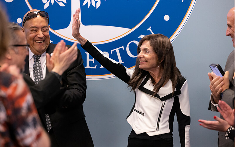 Nancy Segal waves to crowd at the April 23 Academic Senate meeting.