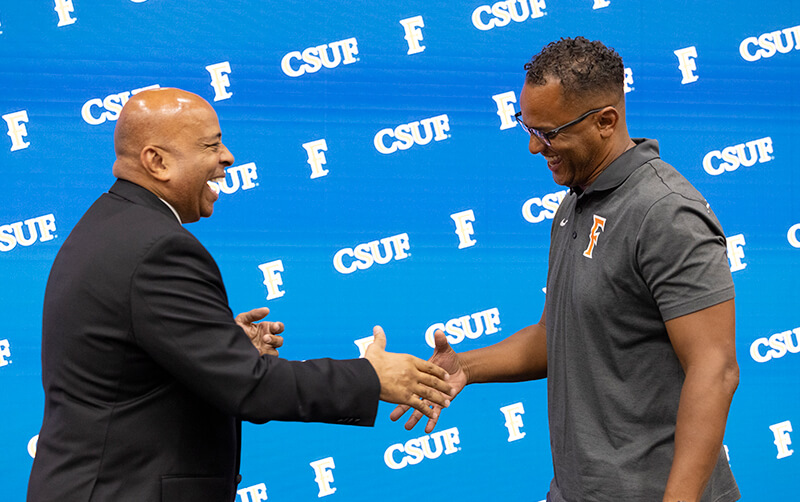 Ronald Rochon and Demian Brown shake hands on stage at the 2026 University Awards Program.