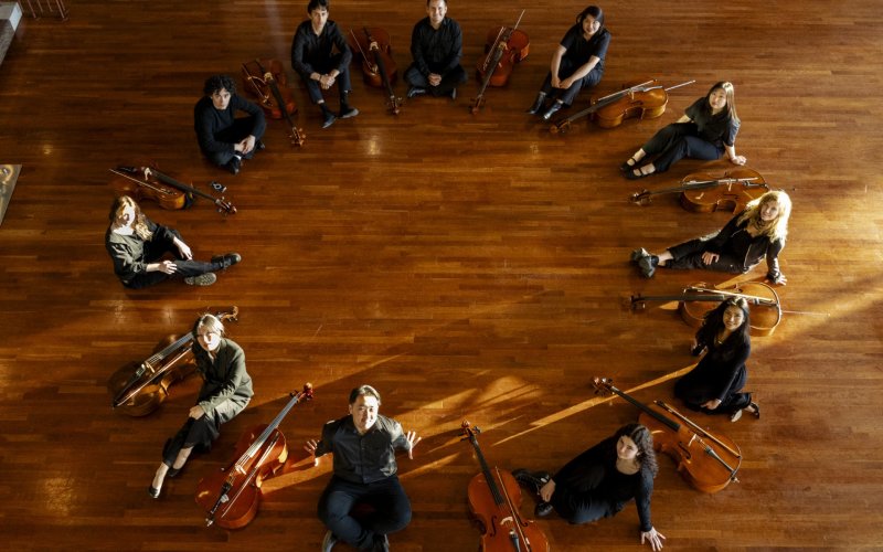 Cello students sit on the floor in a circle