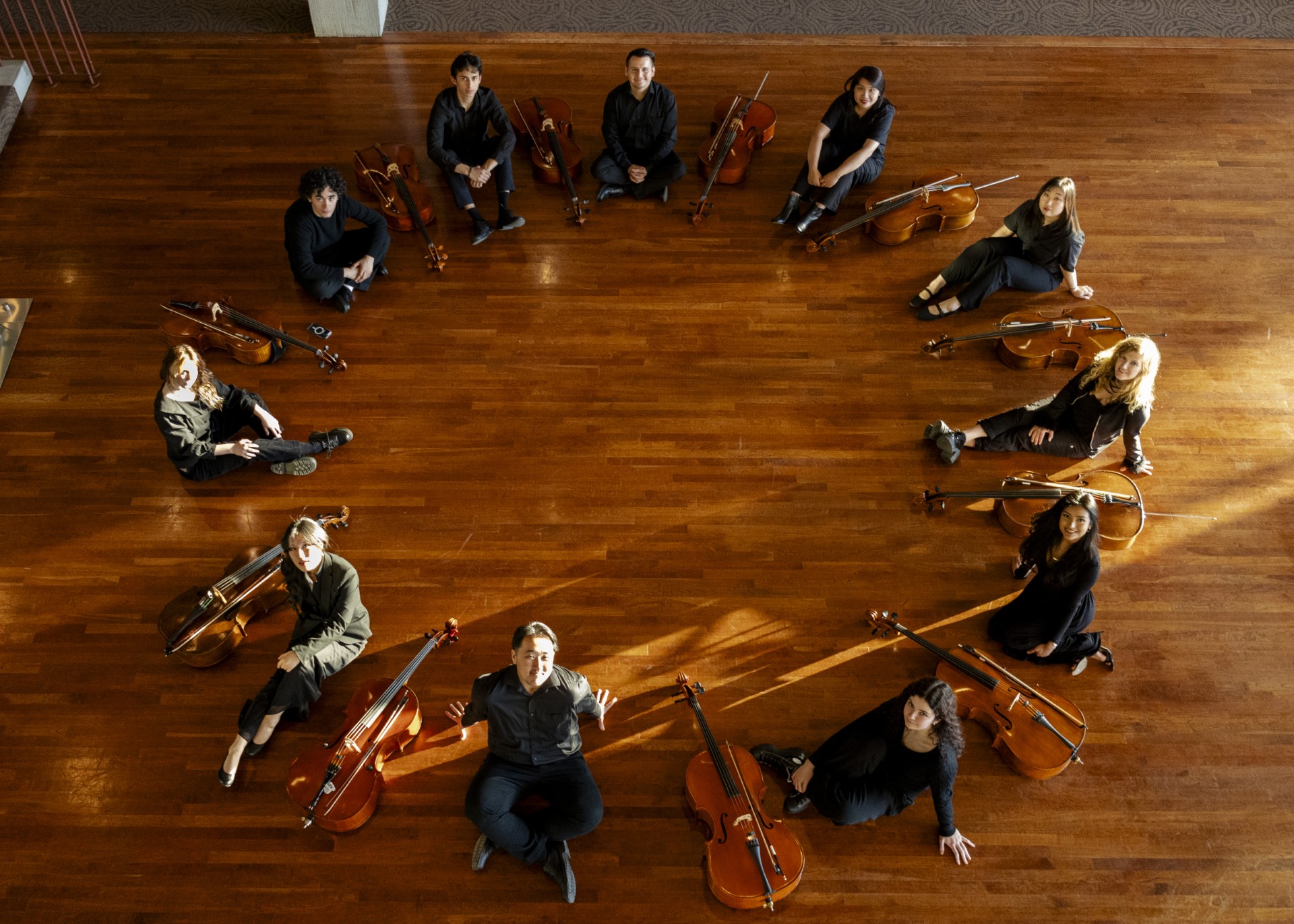 Cello students sit on the floor in a circle