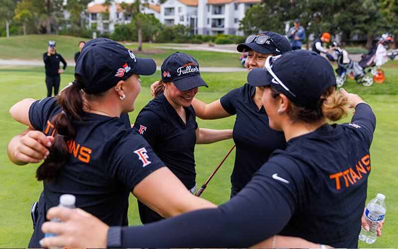 The CSUF women's golf team celebrates on the field.