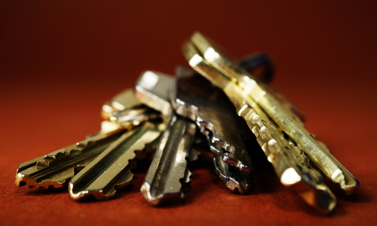 A handful of gold keys on a key ring sit on a table.