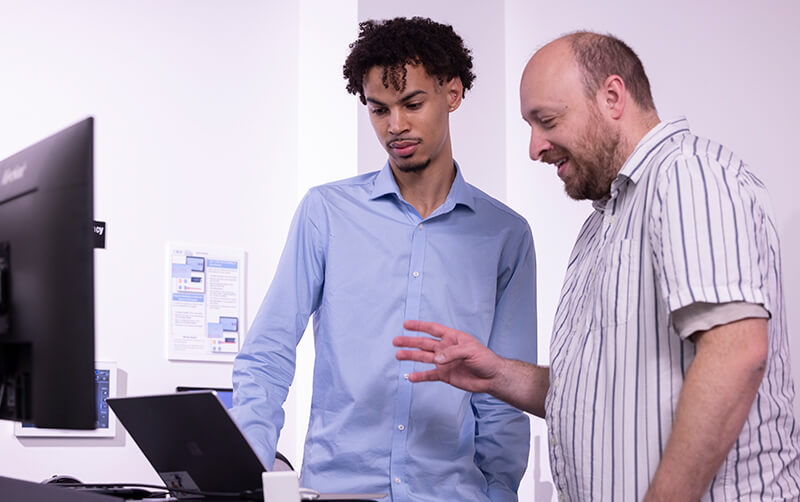 Chemistry student Liam Ryals works on a computer with faculty member Andrew Petit.