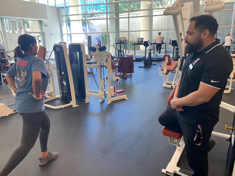Graduate student guides Employee Wellness Program member through a strength exercise.