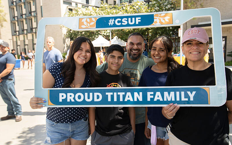 A family holds up a Titan Family license plate frame at CSUF's Move-In Day.