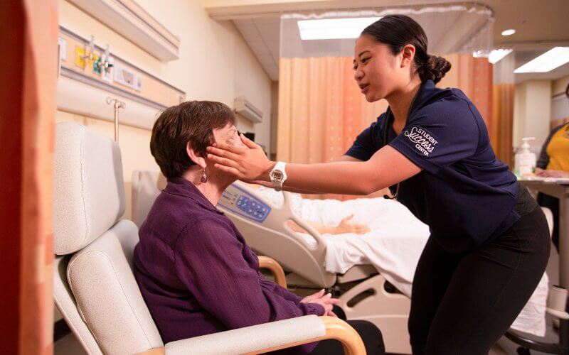 A nursing student checks the vitals of a patient sitting in the Nursing Simulation Lab.