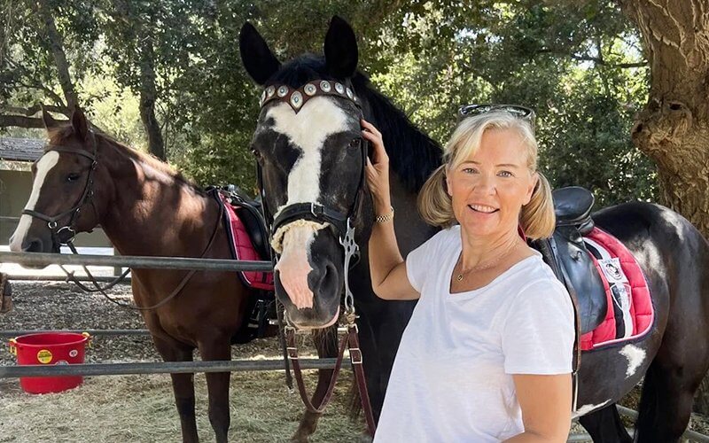 Melinda Blackman stands beside a horse at Back Bay Therapeutic Riding Club.
