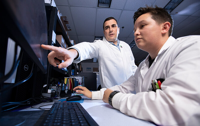 Stevan Pecic and Ryan West study data on a computer in lab.