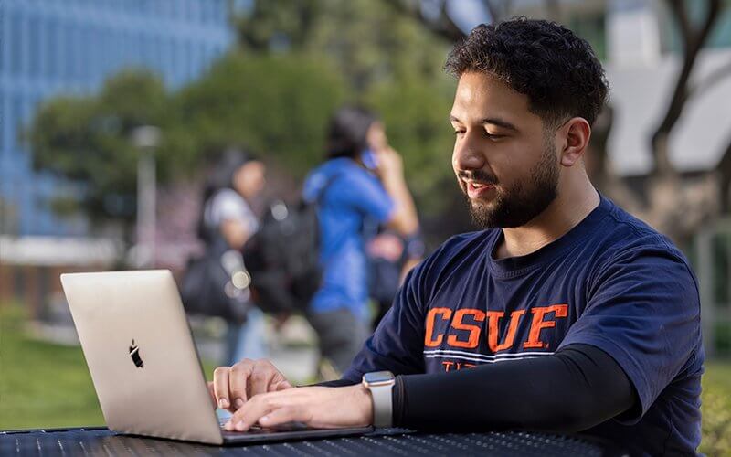 Titan Business Edge student works on laptop on the CSUF campus.