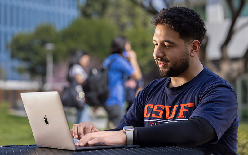 Titan Business Edge student works on laptop on the CSUF campus.