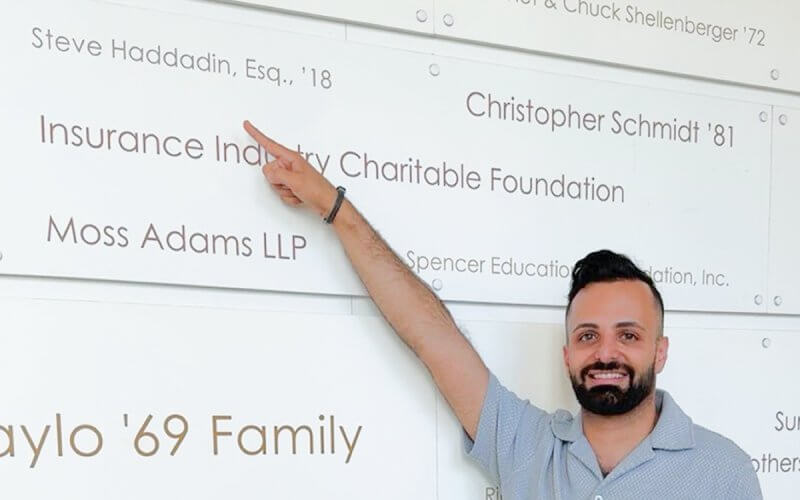 Business alum Steve Haddadin points to his name on the donor wall in the College of Business and Economics.