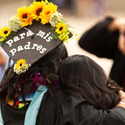 Latina Graduate hugging family memeber.