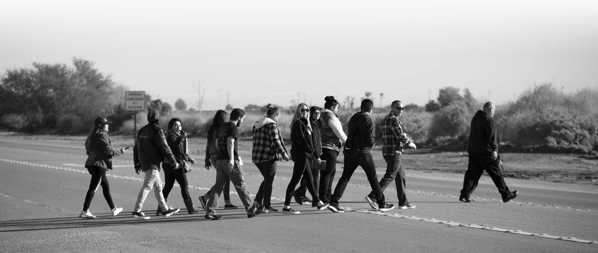 CSUF Students crossing street near border fence